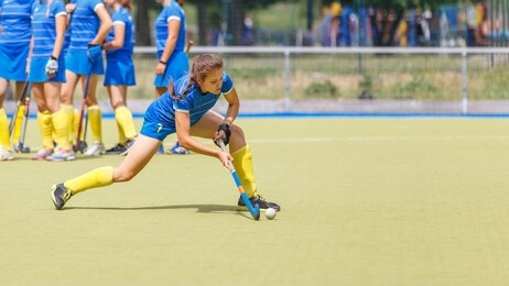 young field hockey female player hitting the ball on the pitch. team sport image with copyspace
