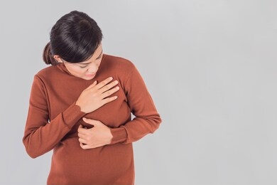 pregnant  asia women use the hand to grasp her chest and feel pain in the chest area.focus on face