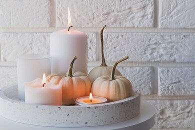 autumn home decor with white pumpkins and burning candles. cozy fall composition
