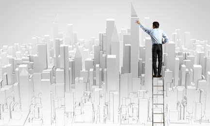 back view of businessman standing on ladder and drawing buildings