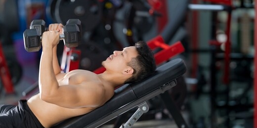 sporty man training with dumbbell in gym 