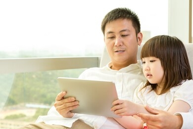father and daughter using tablet together at home