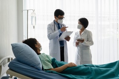 asian doctor teaching medical student who wearing face mask to treat sick patient in the ward in hospital. healthcare and medical school concept