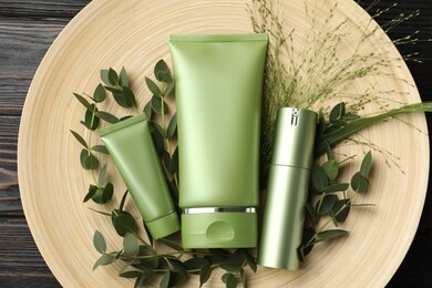 set of cosmetic products and plants on dark wooden table, top view