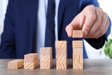 businessman building steps with wooden blocks on table, closeup. career ladder