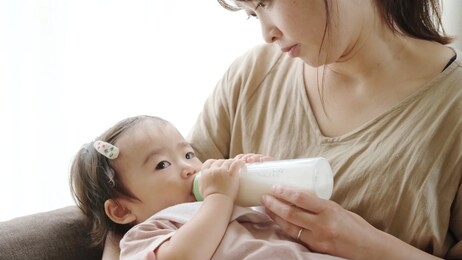 asian baby drinking milk at living room