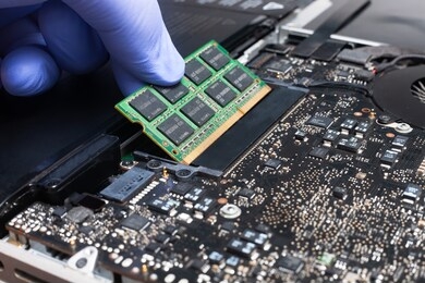 service engineer install new ram memory chips to the laptop. repairing and upgrading laptop concept. close up view.