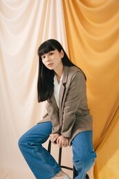 young beautiful asian thai long dark hair woman wearing suit jacket and jeans sit on a chair. fashion portrait.