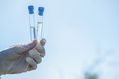 scientist is holding in hands a clear and dirty water test tubes close up.