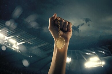 champion. award of victory, male hands tightening the golden medal of winners against cloudy dark sky. sport, competition, championship, winning, achieving the goal. prize for success and honor.