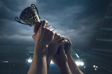 hard work. award of victory, male hands tightening the golden cup of winners against cloudy dark sky. sport, competition, championship, winning, achieving the goal. prize for success and honor.