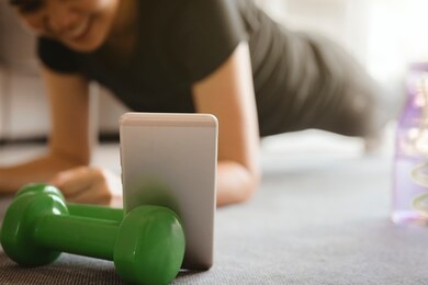 a sporty woman using smartphone during workout at home in the living room. online personal trainer or on mobile phone.sport and recreation concept.