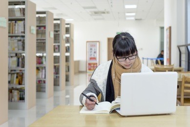 chinese girl reading using a computer in the library 