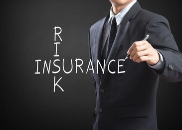 business man writing risk insurance crossword