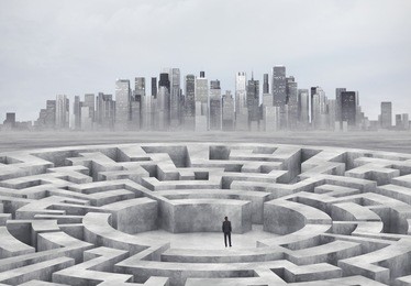 businessman standing in the middle of a maze. big city on a horizon.
