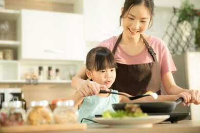 happy family in the kitchen. mother and child daughter preparing a meal including eggs.