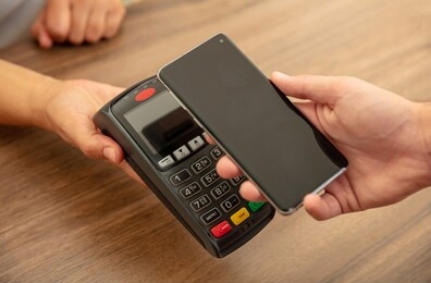 mobile payment, smart phone nfc, near field communication wireless technology. cashier and customer hands with pos machine and smartphone, closeup view