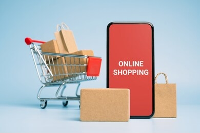 concept online sopping. boxes and shopping bag on trolley with smartphone online shopping screen.