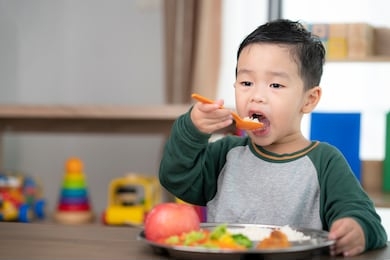 asian student take a lunch in class room by food tray prepared by his preschool, this image can use for food, school, kid and education concept