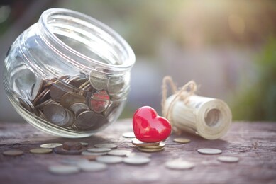 red hearth and money coins on deposit bank book.concept of saving money for health.