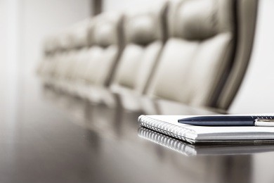 closeup of notepad for agenda kept on table in empty corporate conference room before business meeting