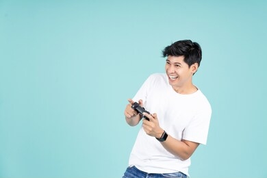 asian man enjoy and have fun play game console standing on green mint pastel color background 