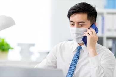 asian young business man speak on smartphone to discuss his work plan in the office