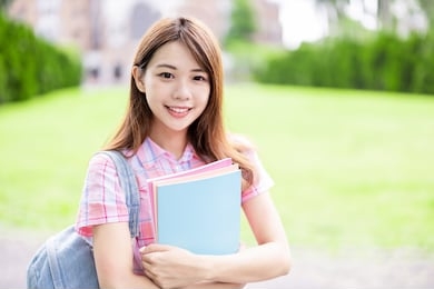 asian college student smile to you with books holding in hands on campus