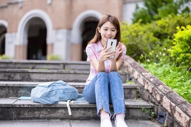 asian college student use mobile smartphone happily on campus