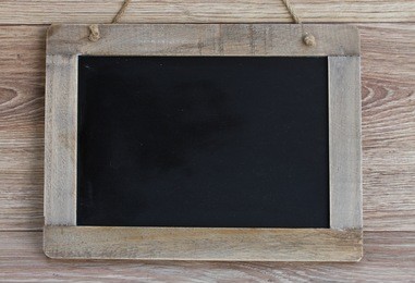 empty black chalkboard hanging on wooden background