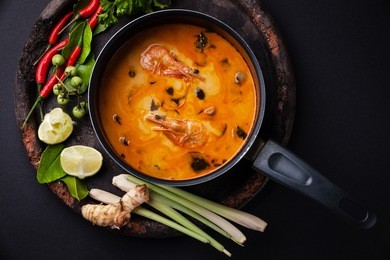 spicy thai soup tom yam with ingredients on dark background