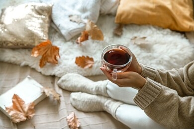 cozy autumn at home, a woman with tea and a book resting. a cozy way of life . body parts in the composition.