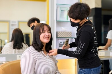 hairdresser giving a new haircut to asia women customer at salon,beautiful cute young plus size female with loose dark hair enjoying