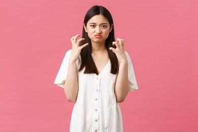 beauty, people emotions and summer leisure concept. mad and tensed young asian woman losing control over emotions, squeez hands angry and grimacing furious, hate someone, pink background