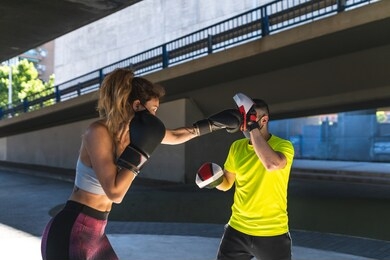 spanish woman training boxing with coach outdoors. beautiful woman boxing with personal trainer. personal trainer boxing. sport concept.