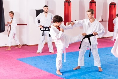 glad  positive   kids in kimonos exercising techniques in pair during taekwondo class at gym