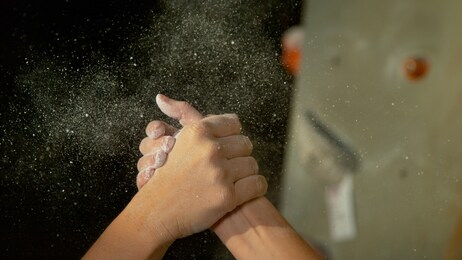 close up, dof: two female athlete climbers shake hands after successfully climbing a difficult route. unrecognizable women celebrate a good rock-climbing session at a new indoor training center.