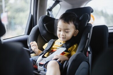 1 year old adorable asian boy alone looking around from car seat in the car portrait. family trips and baby care and safety concept. front view headshot closeup copy space, and blurry background.
