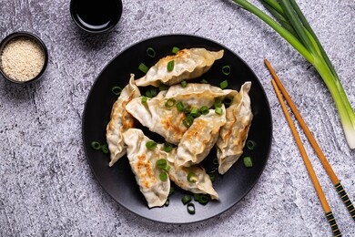 fried dumplings gyoza on a plate on a gray concrete background, top view