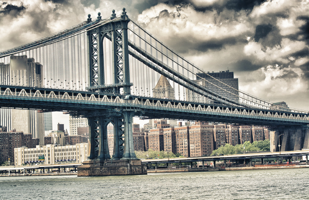 side view of manhattan bridge structure and new york buildings.