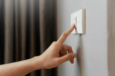close up of female finger is turn off on lighting switch at home. power, energy, saving electrical, copy space. 