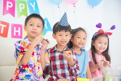 group of asian children eating donut together at birthday party.