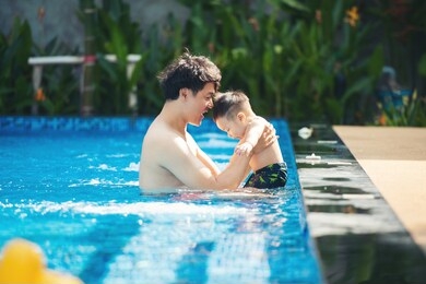 asian father playing with his little son in pool. asia people swim in pool outdoor.