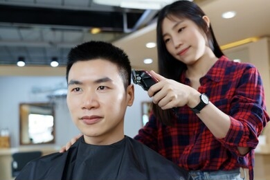 happy asian man use the haircut service in barber shop. woman hairdresser provide service mind. hairdressing equipment is clean. end of quarantine and return to open salon hair work