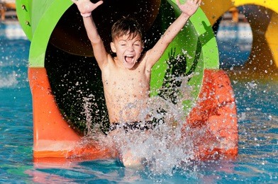 boy has into pool after going down water slide during summer 