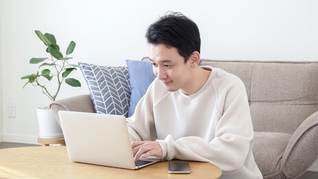 asian man using a computer in the living room