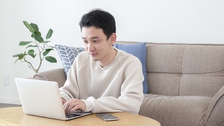 asian man using a computer in the living room