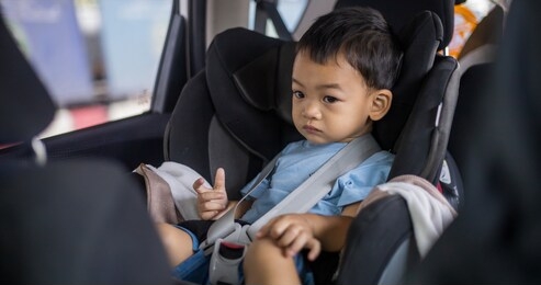 1 year old adorable asian boy alone looking around from car seat in the car portrait. family trips and baby care and safety concept. front view headshot closeup copy space, and blurry background.