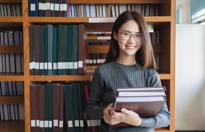 back to school education knowledge college university concept, beautiful female college student holding her books smiling happily standing in library, learning and education concept

