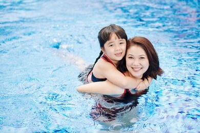 portrait of smiling asian woman giving piggyback ride to her adorable little daughter